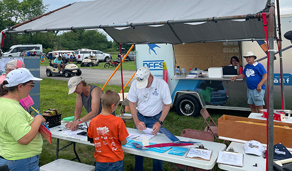 Group setting up model rockets at an outdoor event booth.