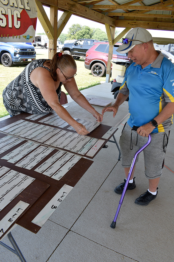 Woman and man arranging signs on a table under a gazebo.
