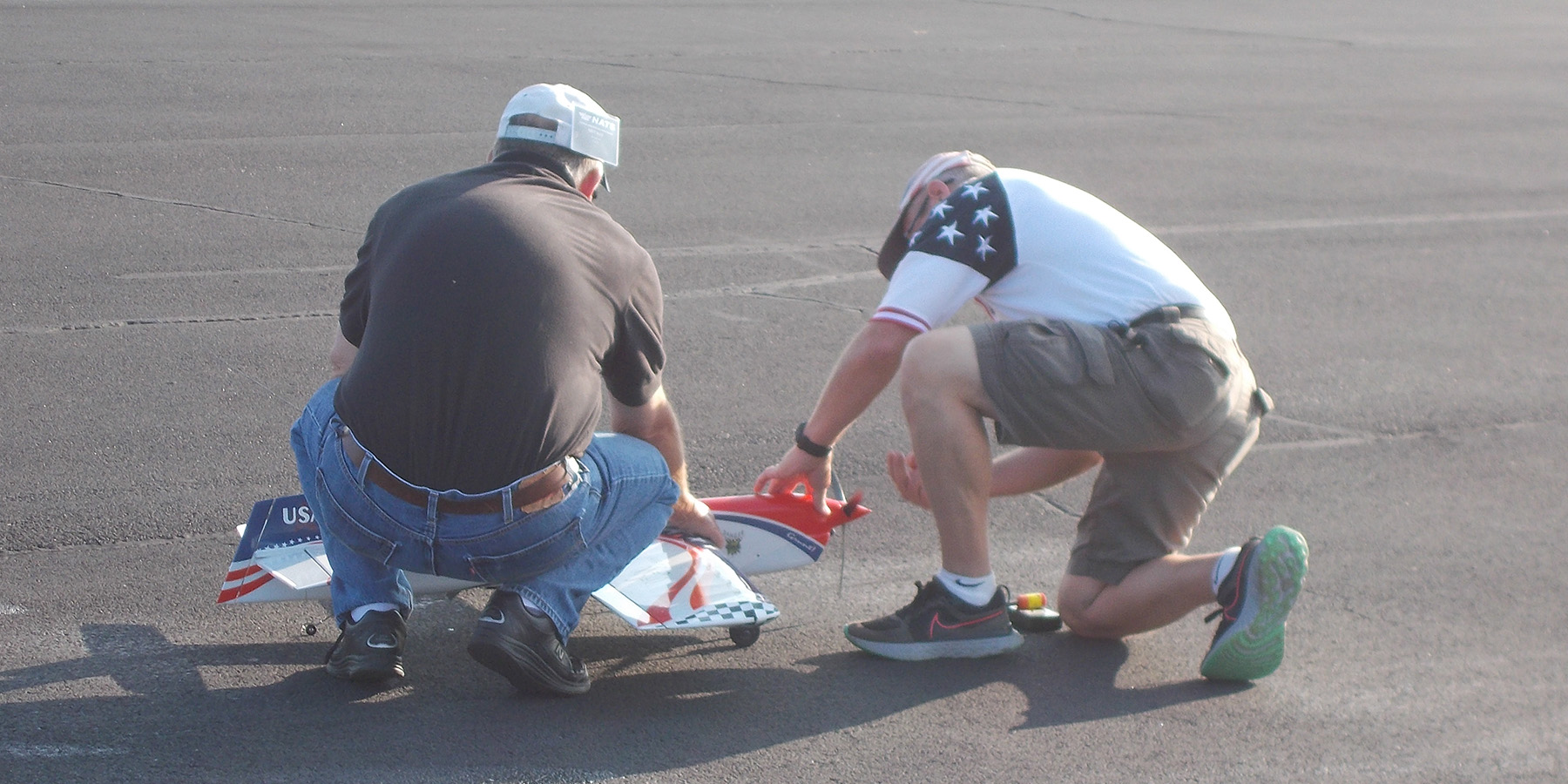 4. David Fitzgerald prepares his airplane while Brett Buck holds it.