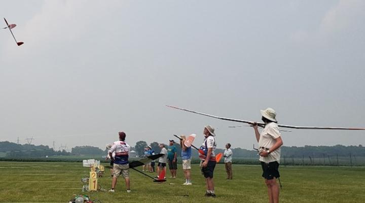 Dave Resinger launches into a steamy day flight. Josh Glaab waits patiently with his sailplane lower to the ground, and Dave Bradley Jr. shoulders his sailplane.
