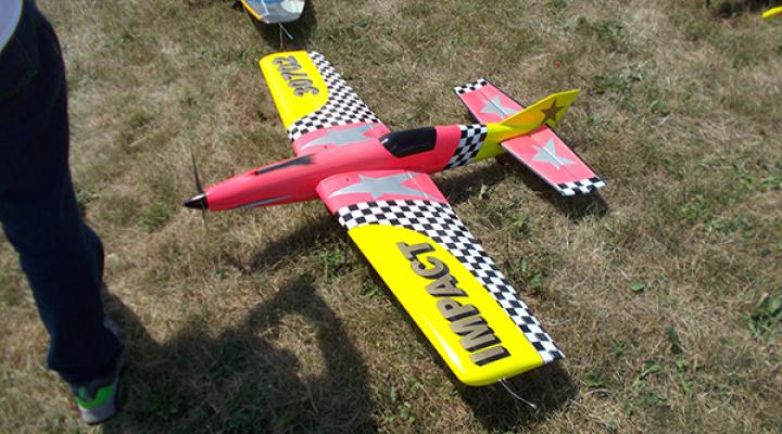 Colorful model airplane on grass, featuring red, yellow, and checkered patterns.