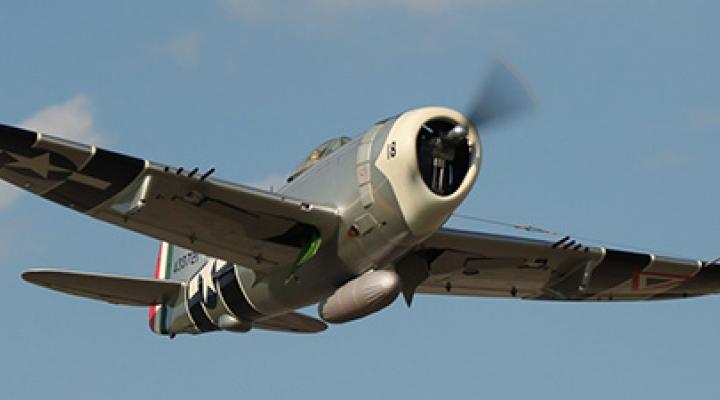 World War II-era fighter plane flying in clear sky.