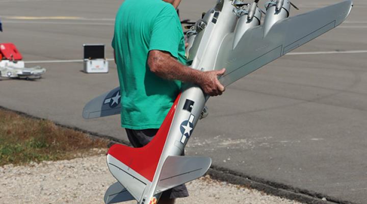 Man holding a large model airplane outdoors.