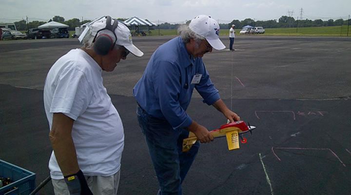 Two men on a tarmac studying chalk markings.
