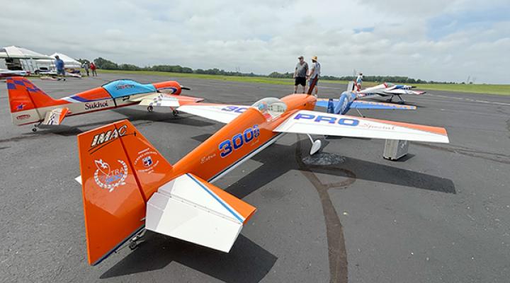 Model airplanes lined up on a runway, with one prominently orange and blue.