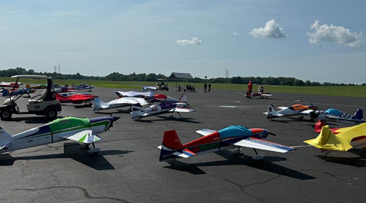 Model airplanes on an airfield, people gather in the background.