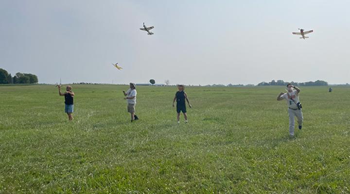 Group flying model airplanes in a field.
