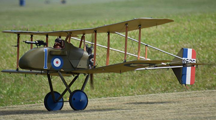 Vintage biplane with blue wheels on grassy field.
